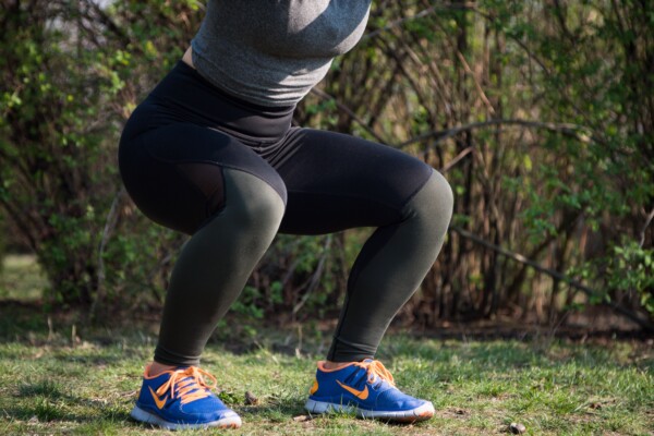 Woman exercising, doing squats, closeup of legs