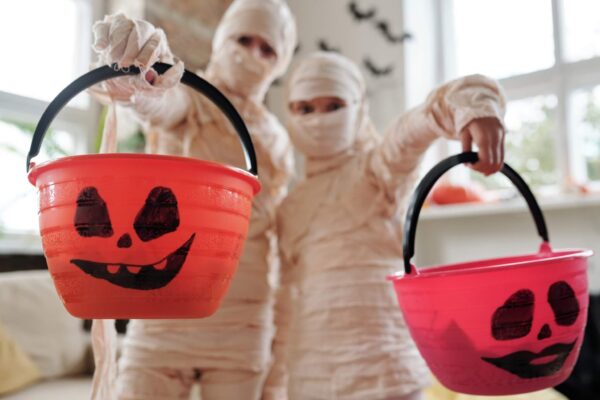 Children in Halloween mummy costumes with trick-or-treat candy buckets
