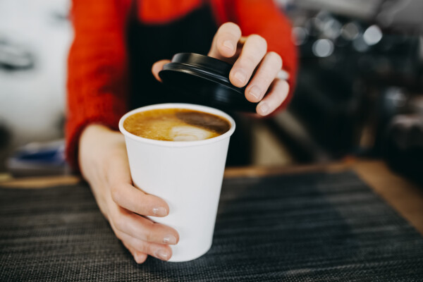 Barista holding coffee in paper cup