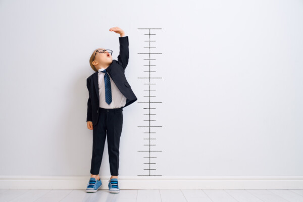 Child measuring how tall he is on height chart