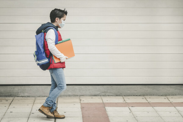 Child walking to school with face mask, gloves during coronavirus / COVID pandemic