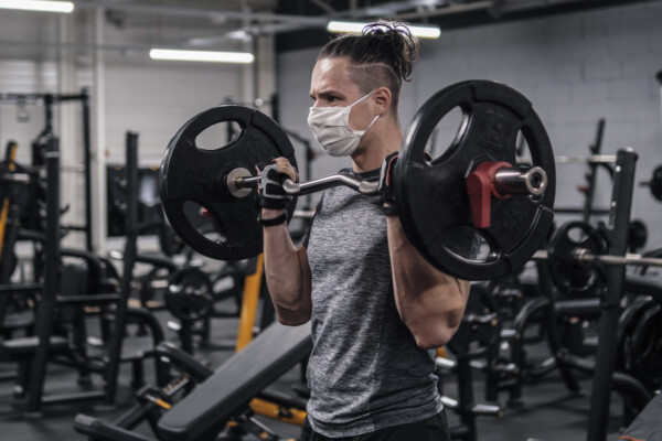 Man working out at gym with face mask on during COVID pandemic