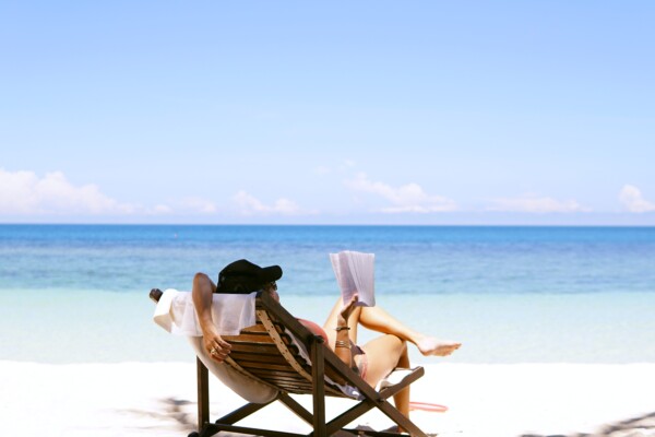 Woman reading a book on the beach, enjoying vacation