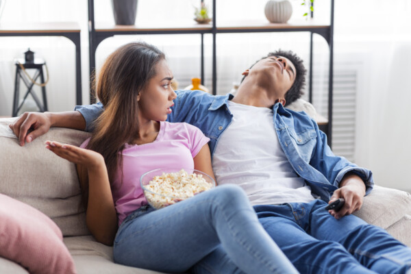 Girlfriend or wife upset with bored partner watching a movie