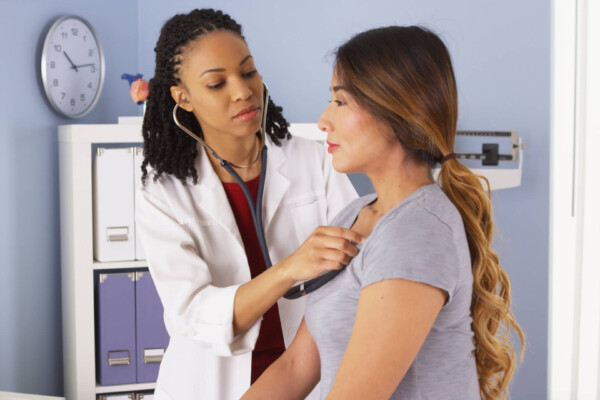 Doctor listening to woman's heart