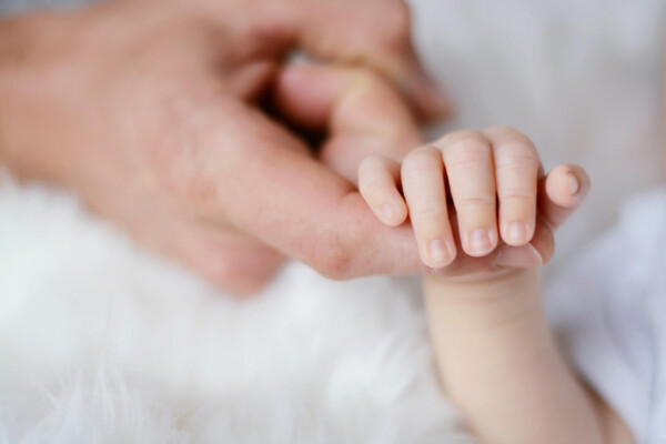 Baby's hand holding father's finger