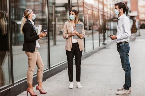 People in face masks talking while social distancing during COVID pandemic