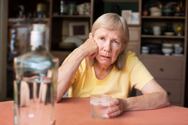 Older woman drinking alcohol alone