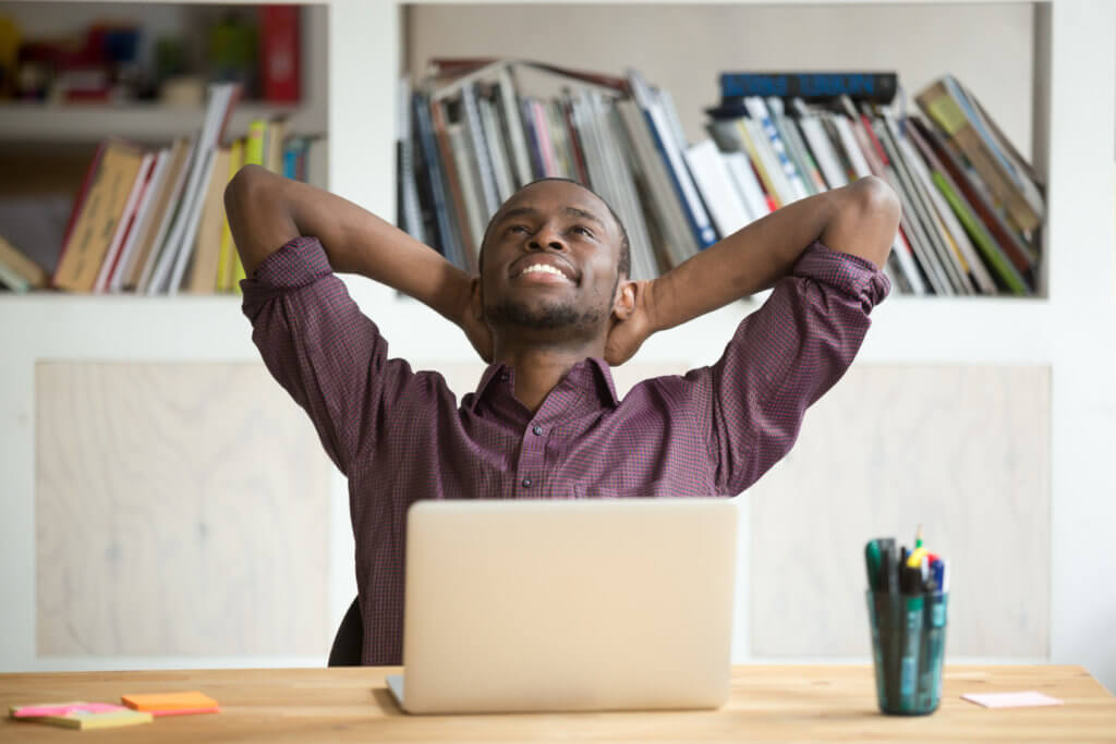 Man daydreaming at work desk, happy