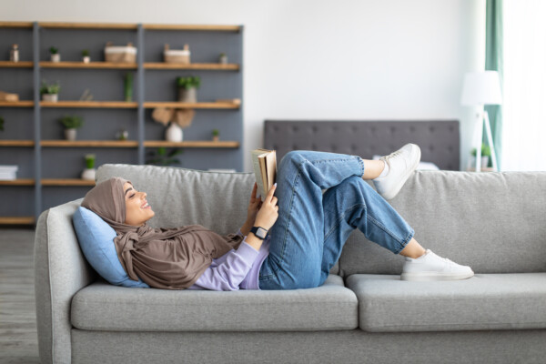 Muslim woman reading on couch