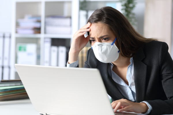 Woman in mask stressed, upset while looking at computer