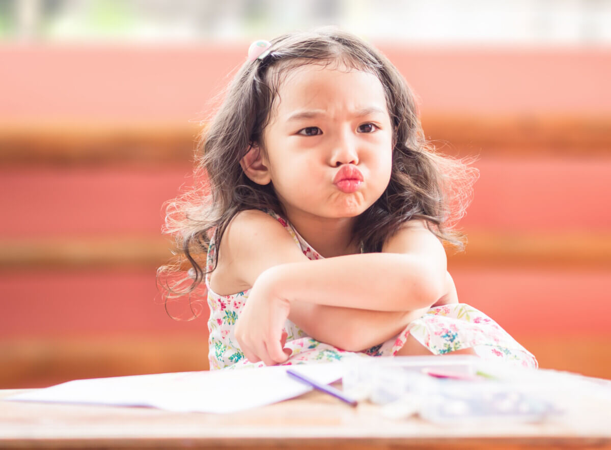 Angry little cute girl with cross one’s arm.The emotion of a chi