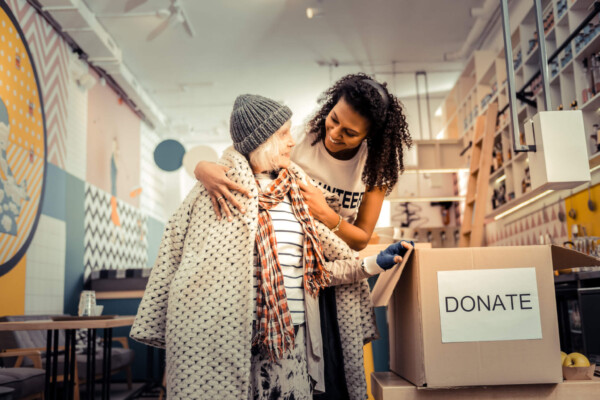 Volunteer helping homeless woman with charity donations