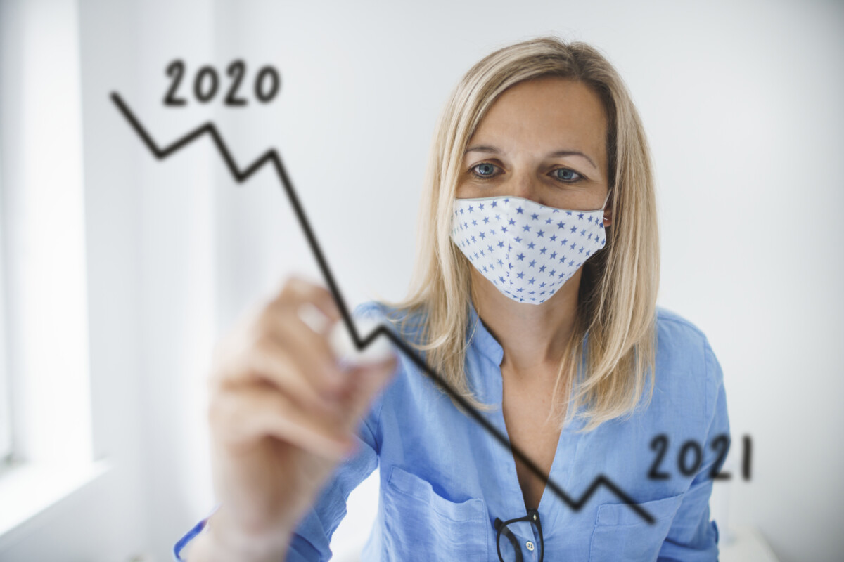 Business woman with face mask drawing falling graph for 2021 during corona crisis