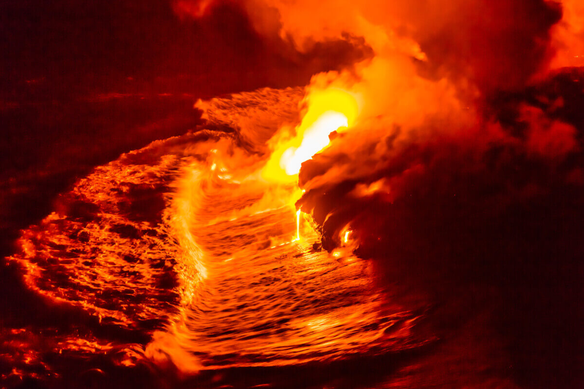 Lava flow pouring into Hawaii ocean at night. Lava falling in ocean waves in Hawaii from Hawaiian Kilauea volcano at night. Molten lava washed by the pacific ocean water crashing in, Big Island, USA.