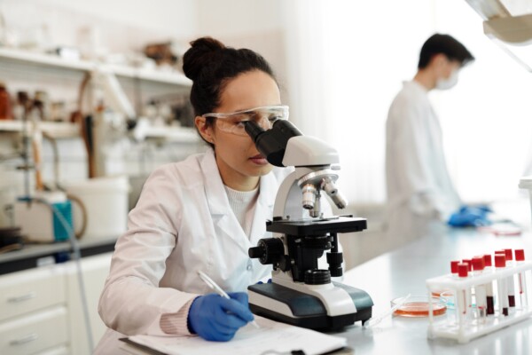 Woman looking through microscope in lab