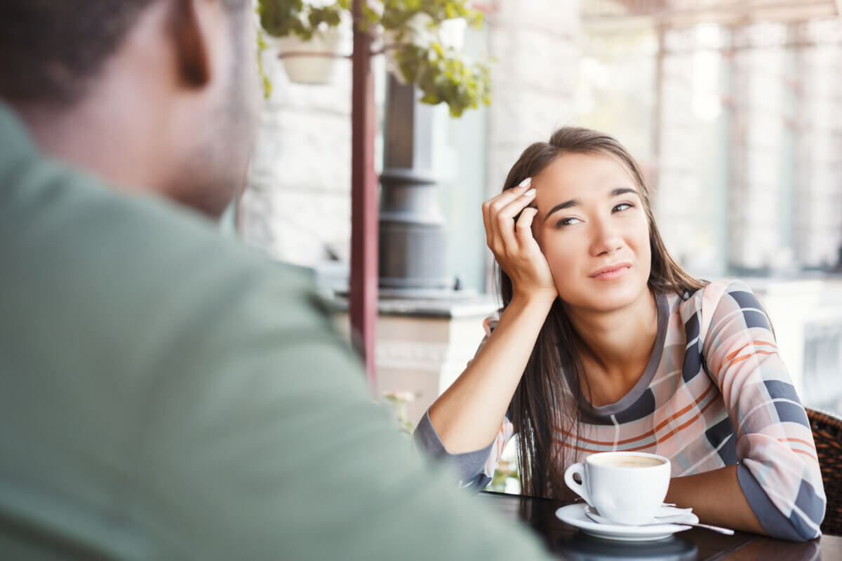 Young bored womanl drinking coffee on date at a cafe
