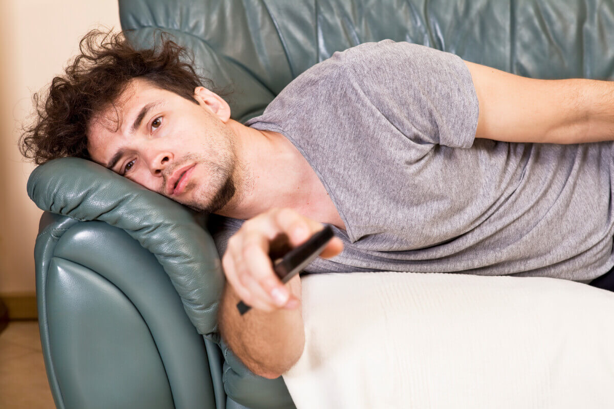 Man watching TV on couch, couch potato