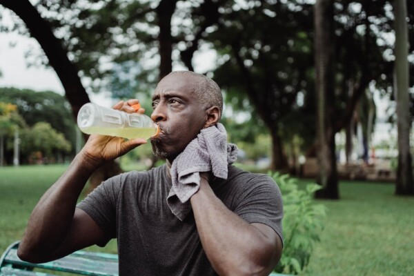 Man drinking bottled water on hot day while exercising