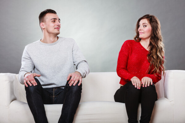 Shy woman and man sitting on sofa. First date.