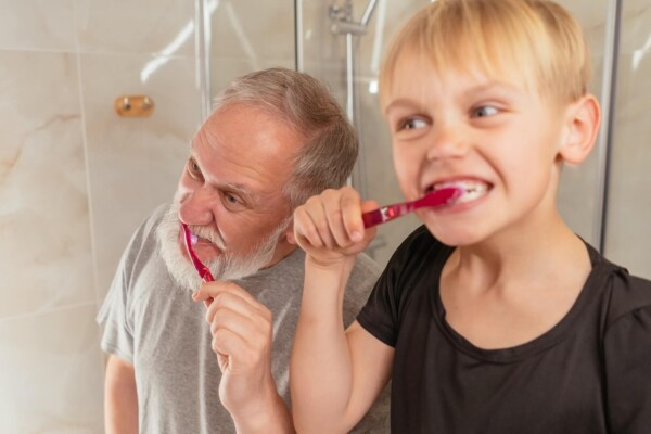 A child brushing teeth with an older family member