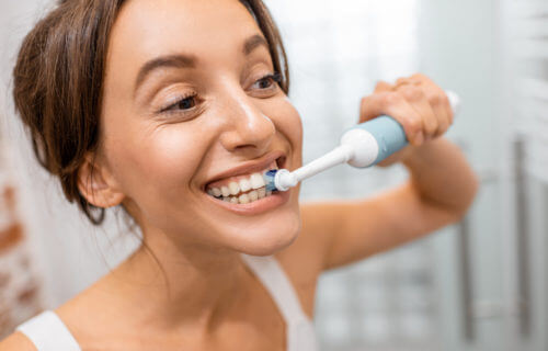 Woman brushing teeth with electric toothbrush