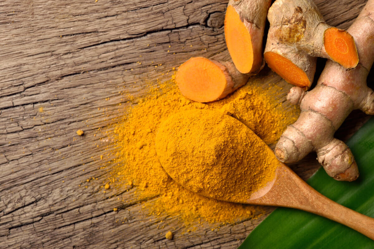 Flat lay (top view) of Turmeric (curcumin) powder in wooden spoo