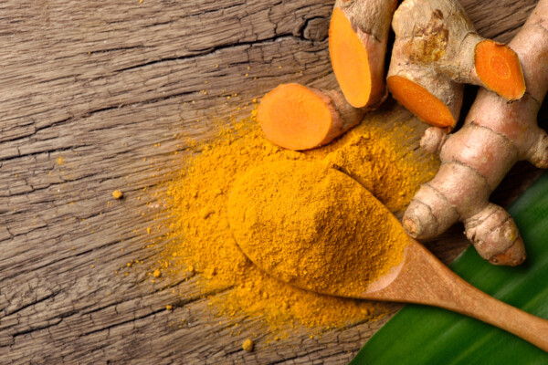 Flat lay (top view) of Turmeric (curcumin) powder in wooden spoon