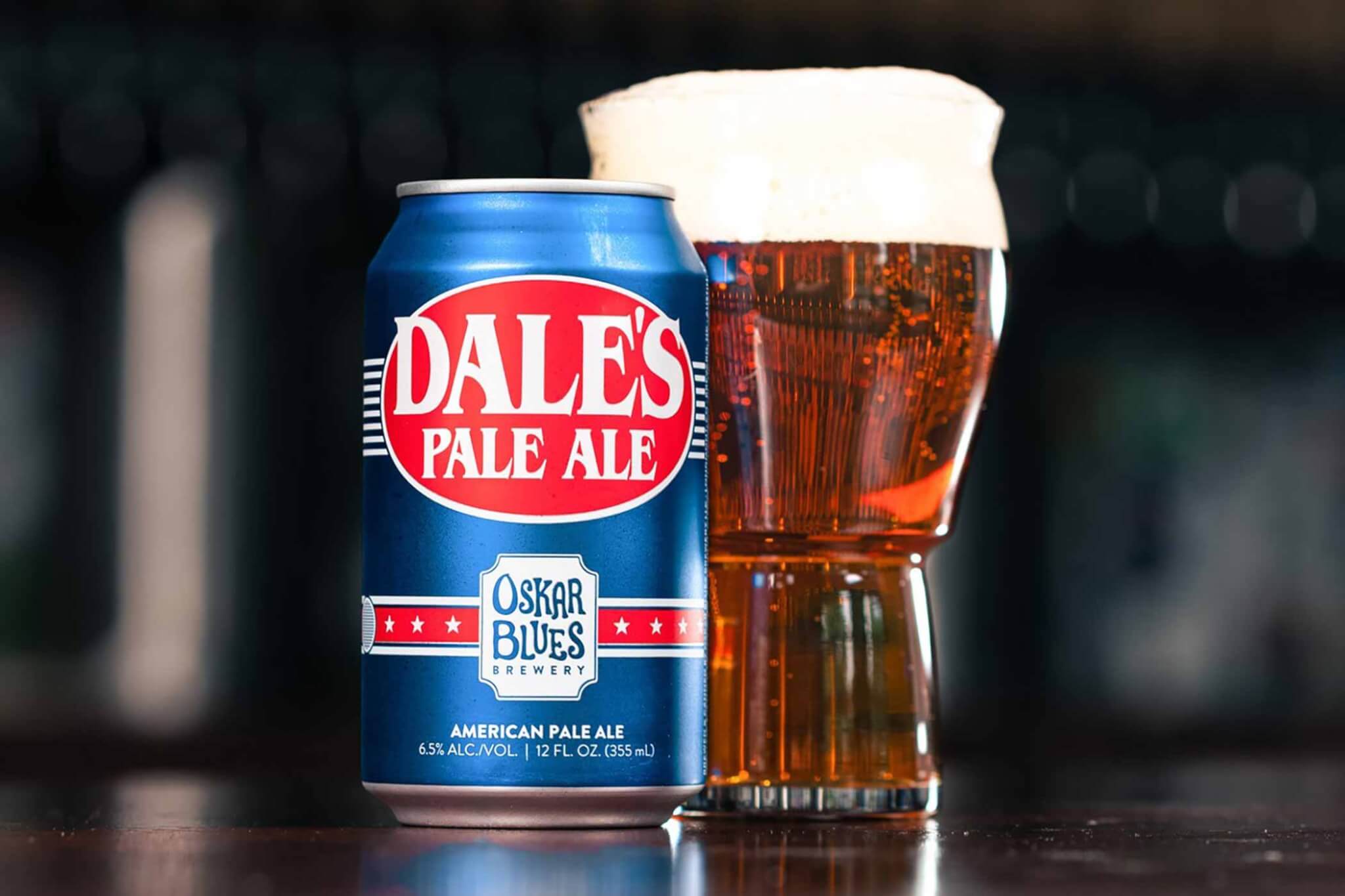 red white and blue beer can with glass on table