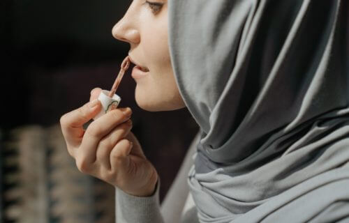Woman putting on lip gloss