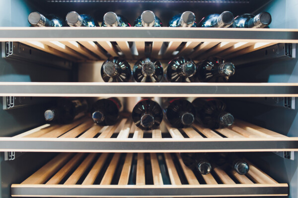 Wine fridge with several bottles on the racks.