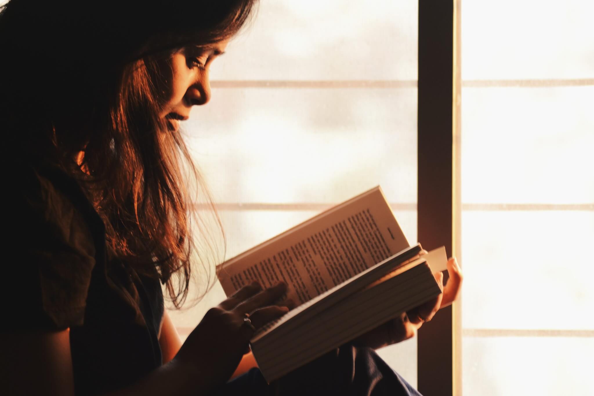 Woman reading a book by the window