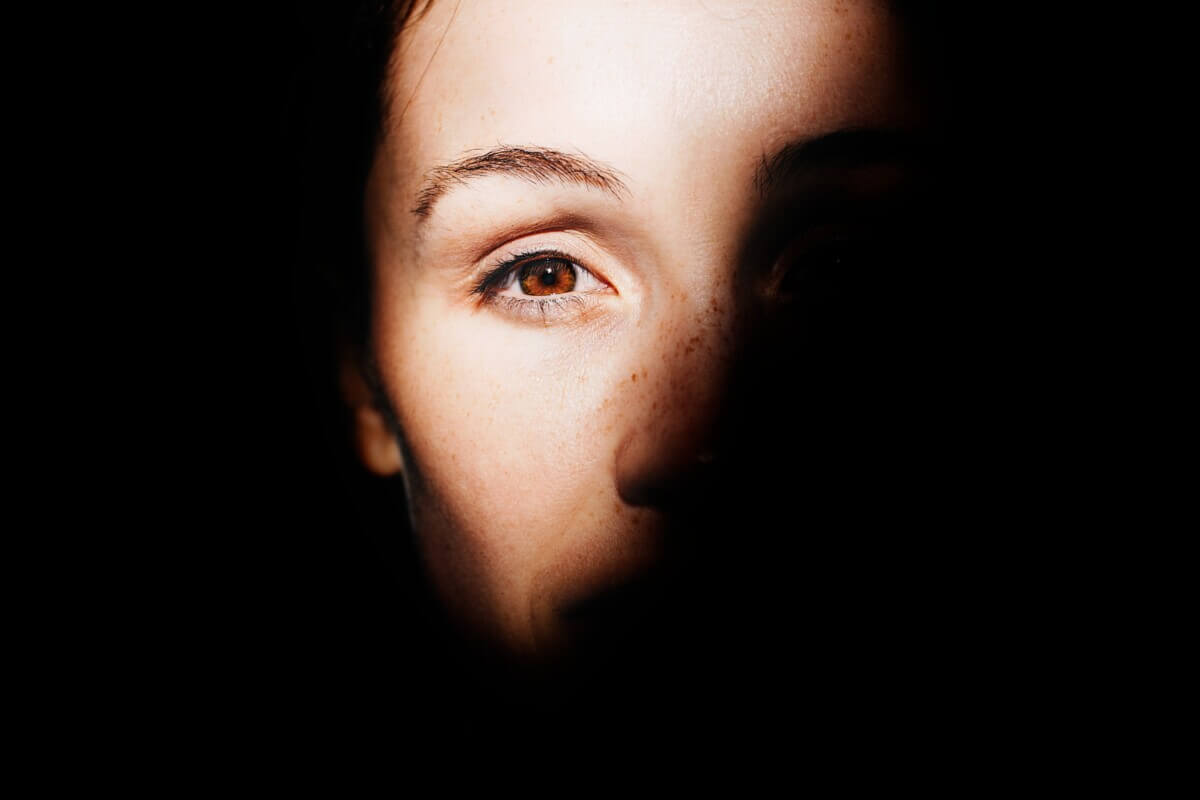 Woman’s face half-covered by shadow so you can only see her eye