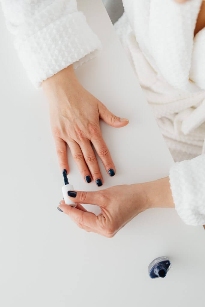 Woman giving herself a manicure, painting her nails
