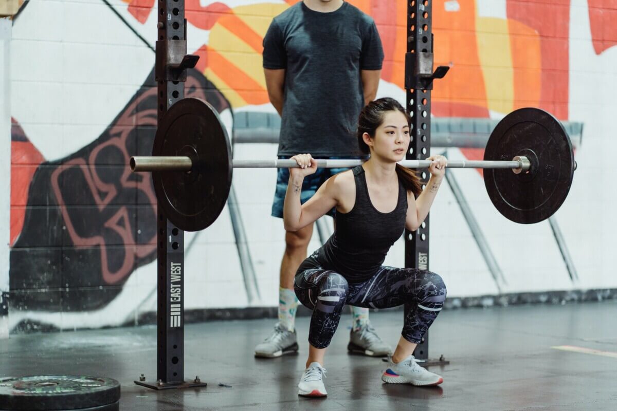 Woman doing barbell squats at the gym.
