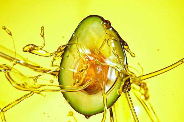 Avocado with oil splashing around it
