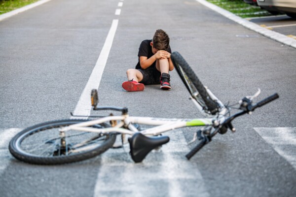 Boy crying after falling off of his bike on the street and getting injured