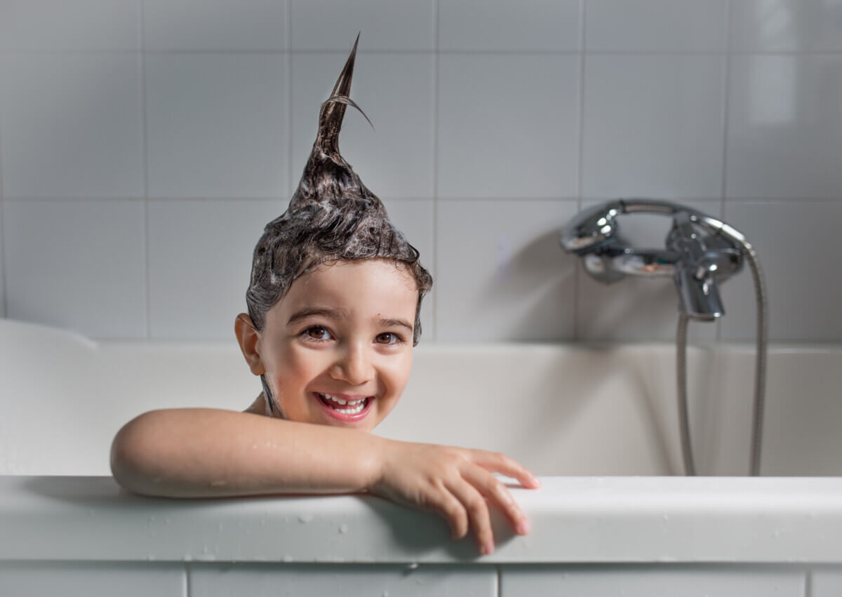 Child taking a bath with shampoo making hair stick up