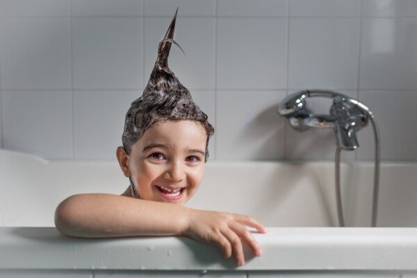 Child taking a bath with shampoo making hair stick up