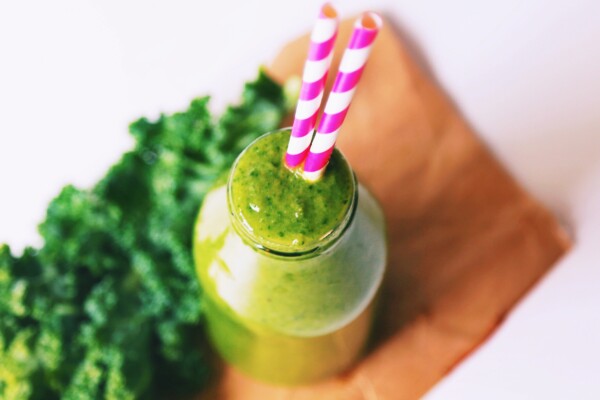 Delicious green smoothie in a bottle with straws