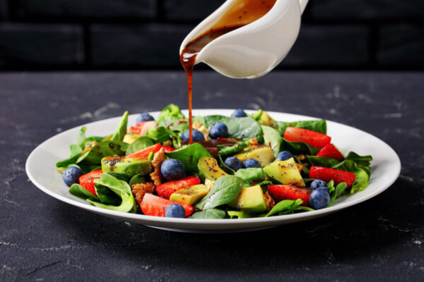Dressing being poured onto a salad