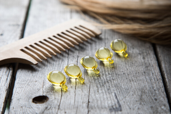 Hair growth vitamins or supplements next to comb