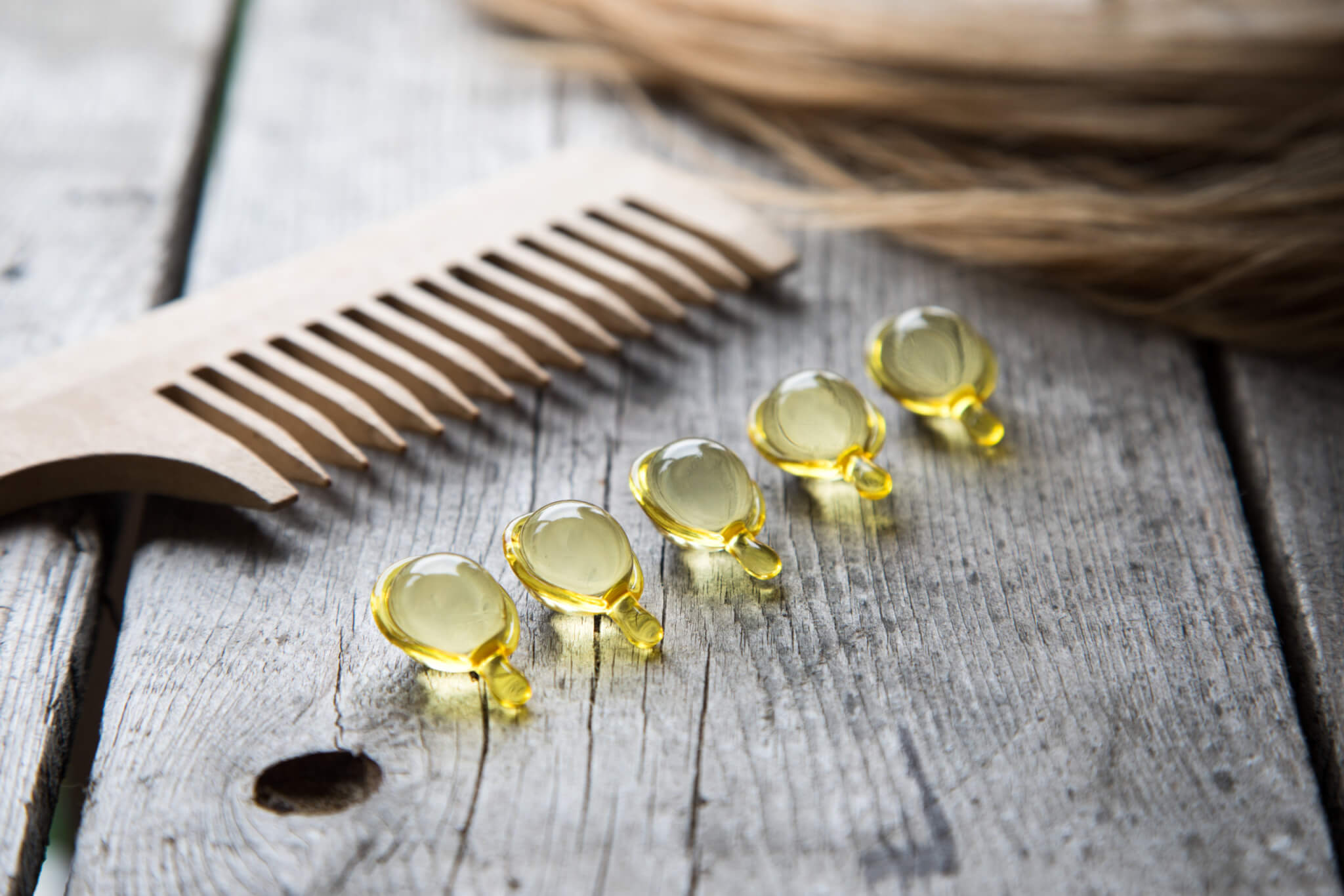 Hair growth vitamins or supplements next to comb
