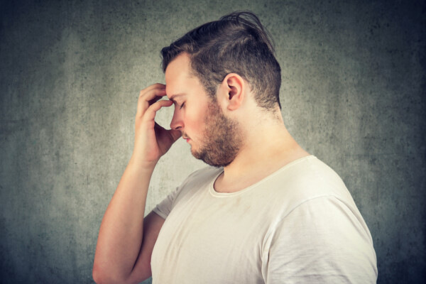 Overweight man with obesity stressed, tired, having a headache