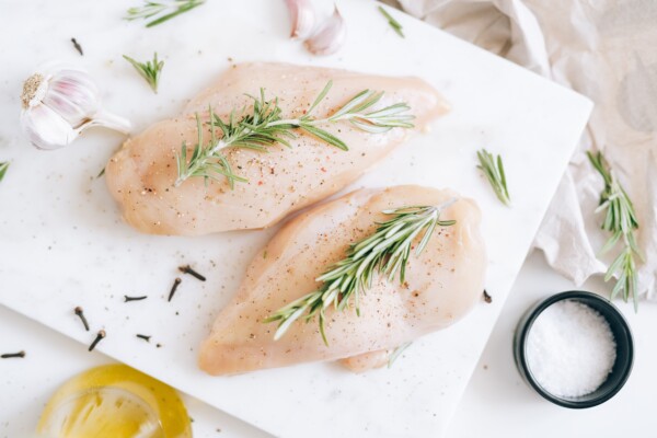 Raw chicken breasts being marinated and prepared