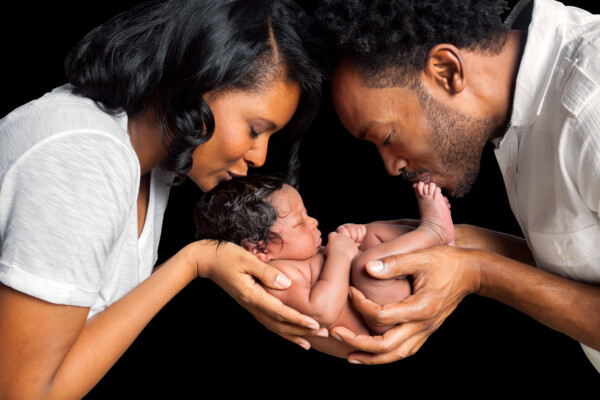 Newborn baby being held and kissed by parents
