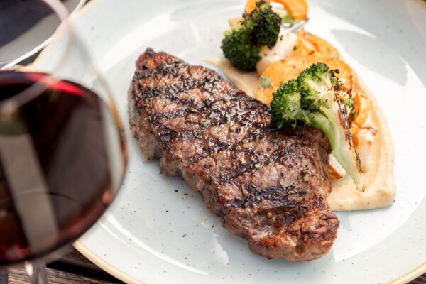 A plate of steak with wine