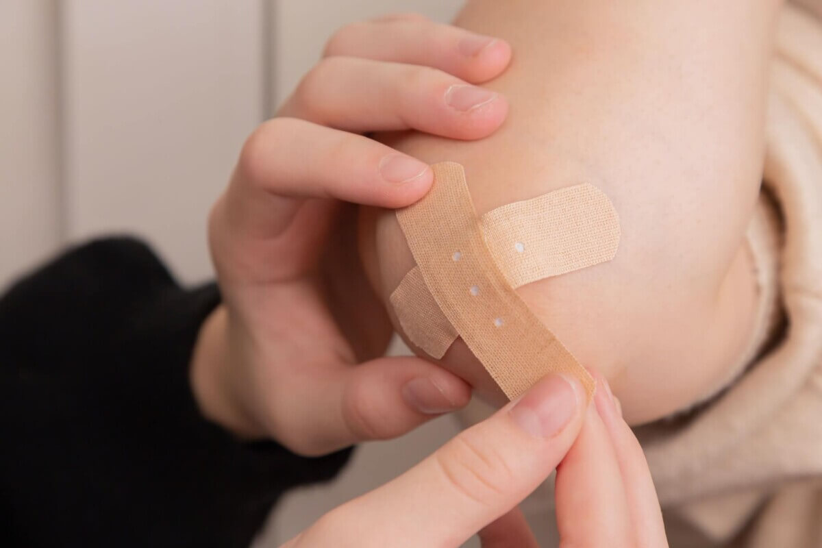 Person puts bandage on someone's elbow.