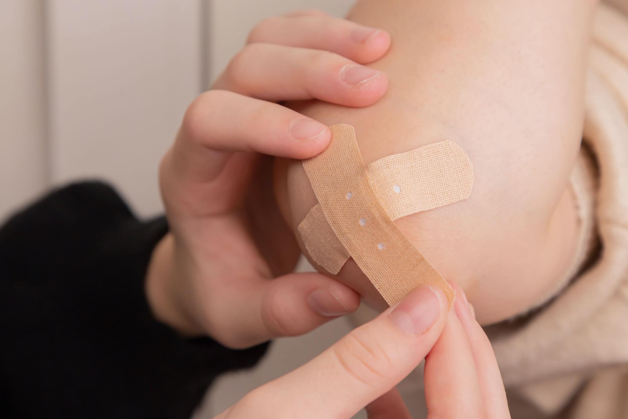 Person puts bandage on someone's elbow.