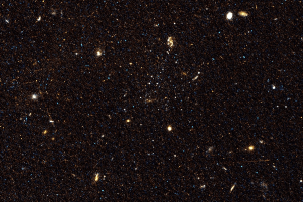Image of space where three faint dwarf galaxies sit near a spiral galaxy.
